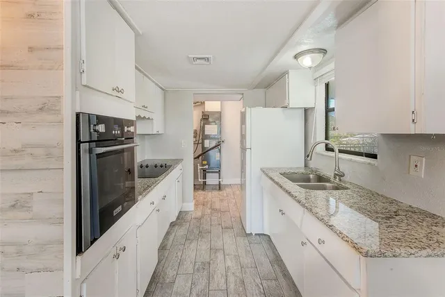 a kitchen with granite countertop a sink stove and refrigerator