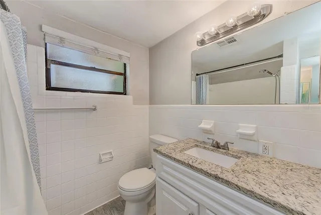a bathroom with a granite countertop toilet sink and mirror