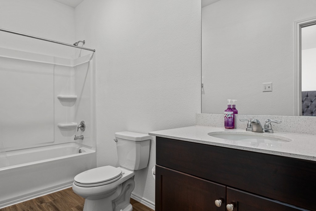205 Rooster Way Jarrell, TX 76537 - Photo 10 of 29 Full bath featuring tub / shower combination, a textured wall, dark wood-style floors, and vanity