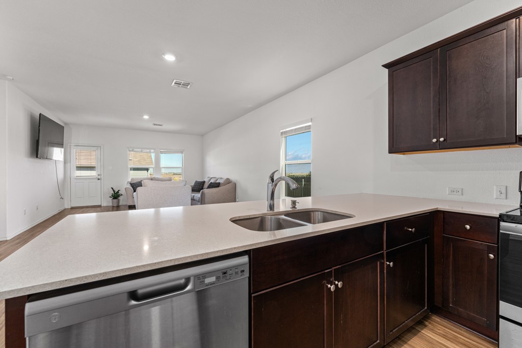 205 Rooster Way Jarrell, TX 76537 - Photo 28 of 29 Kitchen with light wood finished floors, stainless steel appliances, dark brown cabinets, open floor plan, and plenty of natural light