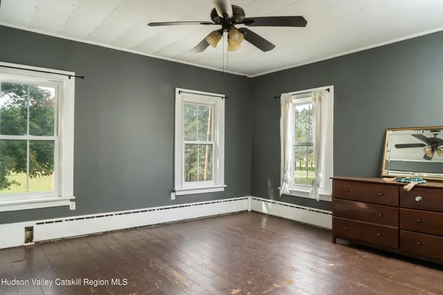 a view of an empty room with a window and wooden floor