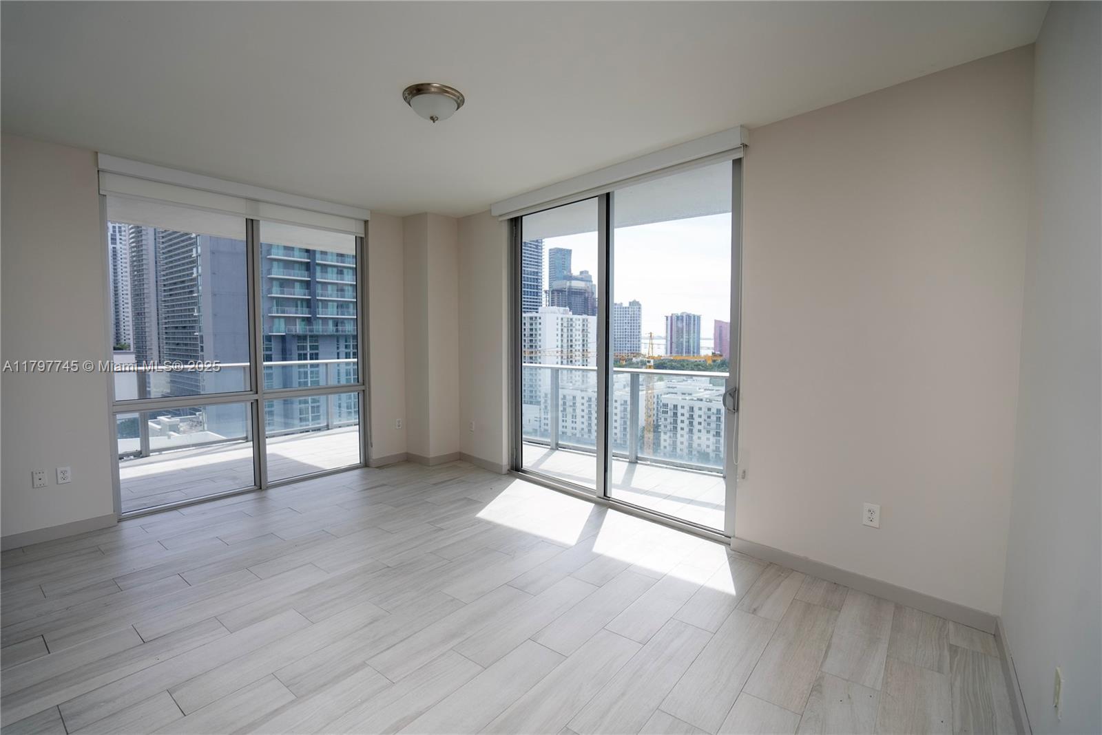 1010 Southwest 2nd Avenue, Unit 1703 Miami, FL 33130 - Photo 5 of 24 a view of an empty room with wooden floor and a window