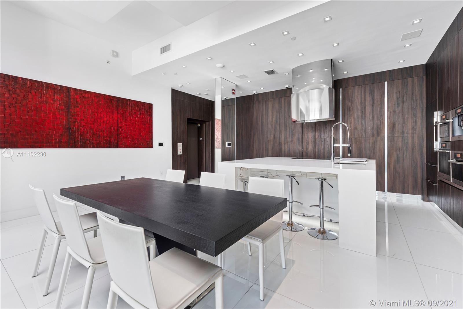 900 Brickell Key Boulevard, Unit 2902 Miami, FL 33131 - Photo 25 of 32 a kitchen with stainless steel appliances a table chairs and a refrigerator