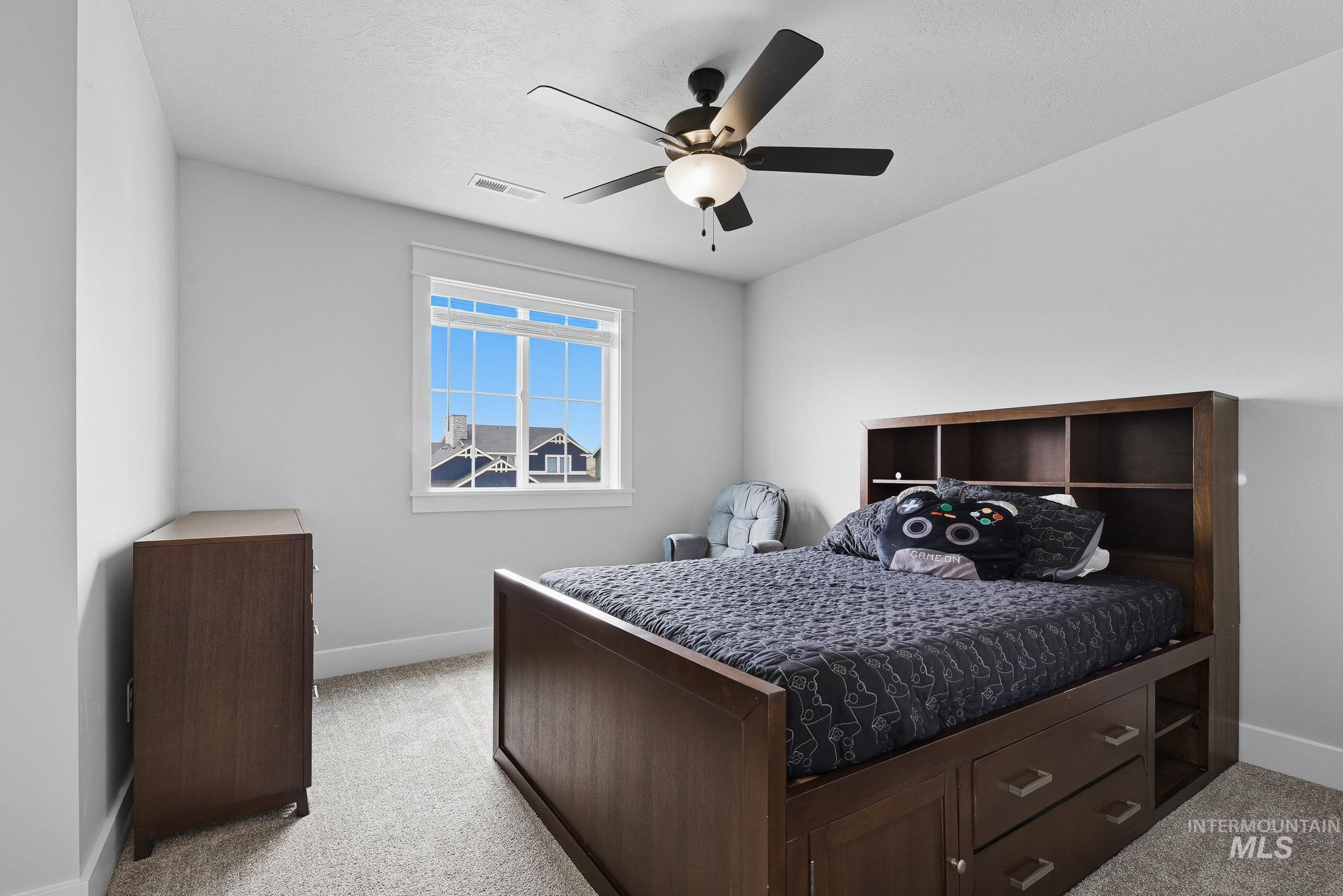 5676 East Zaffre Ridge Street Boise, ID 83716 - Photo 39 of 50 Bright room featuring a multi-pane window, neutral-toned carpeting, white baseboards, and a ceiling fan with integrated lighting