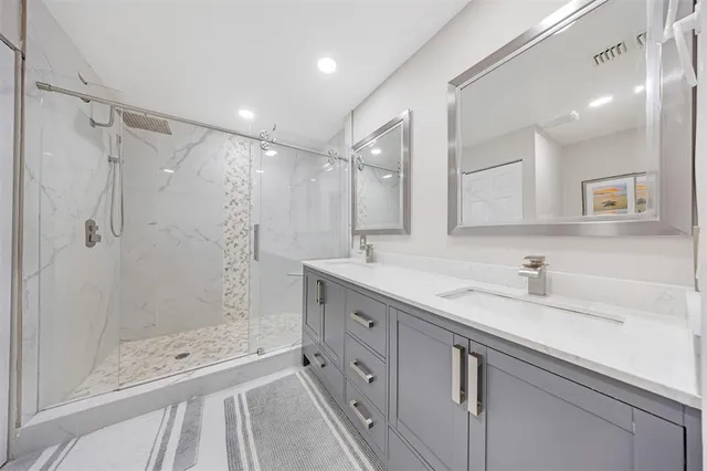 a bathroom with a double vanity sink and mirror with shower