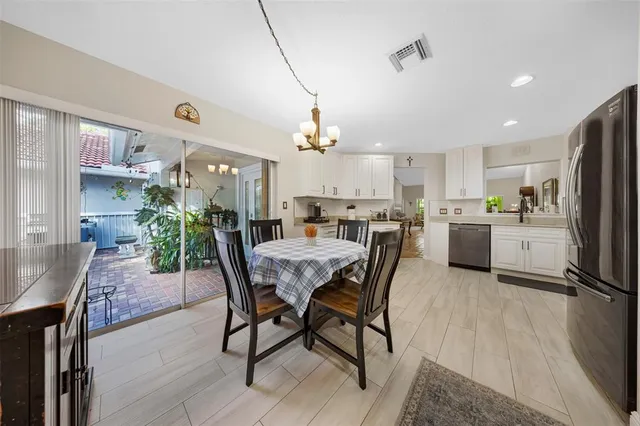 a view of a dining room and livingroom with furniture a rug a potted plant and a chandelier
