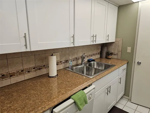 a kitchen with white cabinets and sink
