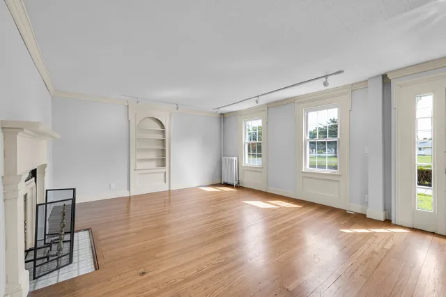 a view of empty room with wooden floor and window