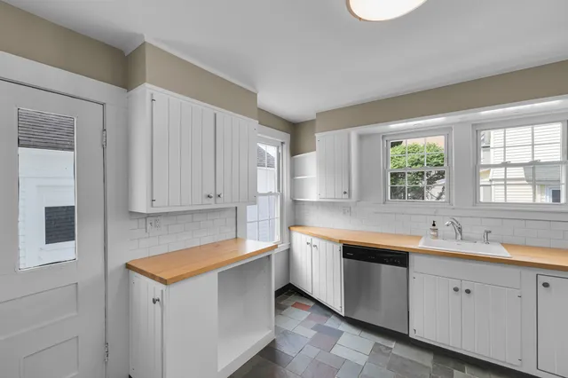 a kitchen with a sink dishwasher window and cabinets