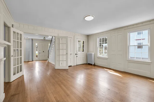 a view of an empty room with window and wooden floor
