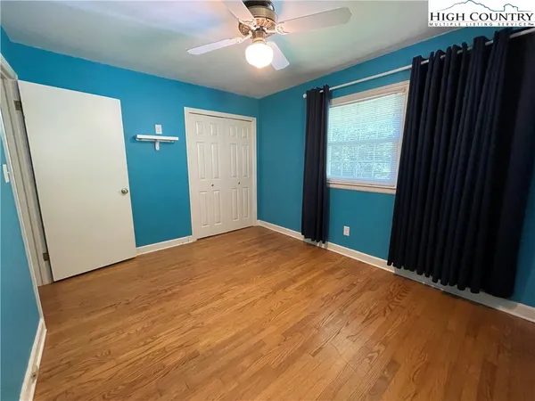 an empty room with wooden floor cabinet and windows