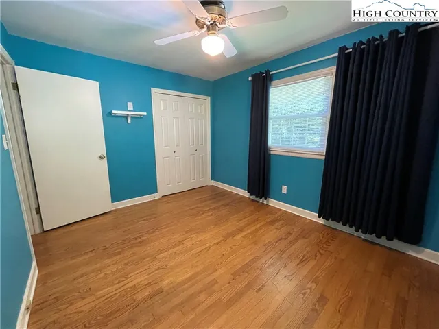 an empty room with wooden floor cabinet and windows