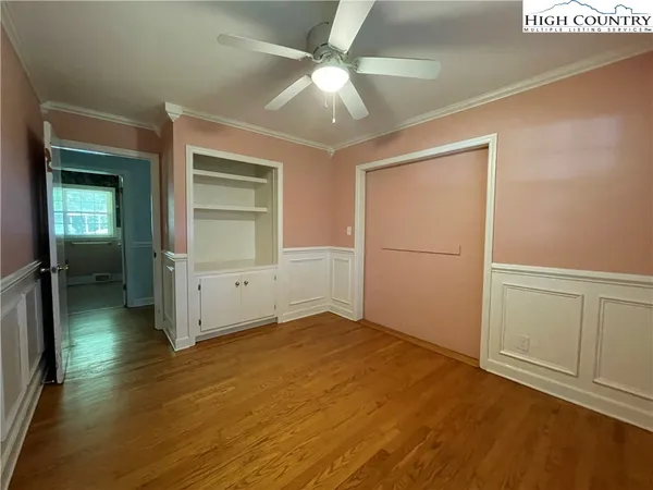 an empty room with wooden floor fan and windows