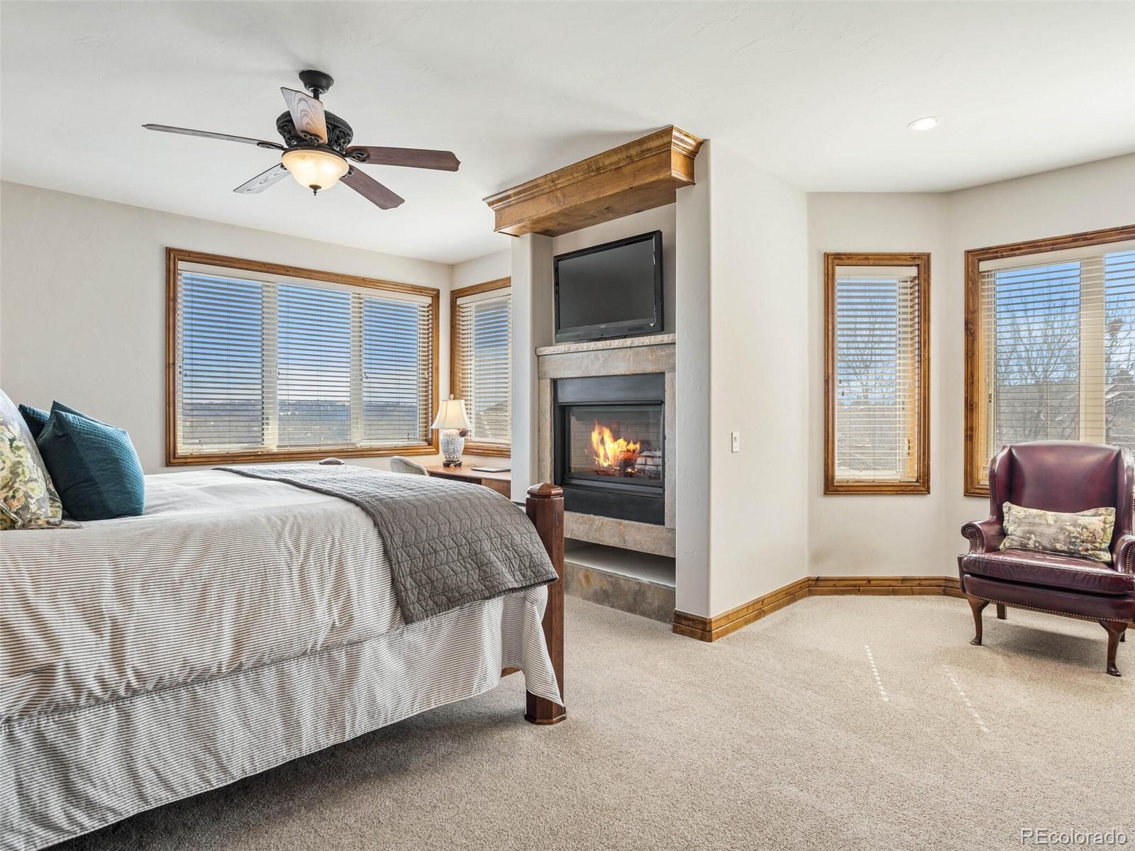 1176 Buffalo Ridge Road Castle Pines, CO 80108 - Photo 18 of 37 a spacious bedroom with a bed and a ceiling fan