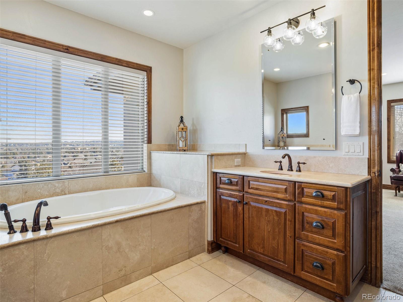 1176 Buffalo Ridge Road Castle Pines, CO 80108 - Photo 20 of 37 a spacious bathroom with a tub sink and mirror