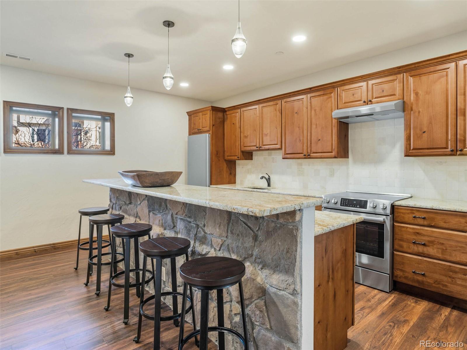 1176 Buffalo Ridge Road Castle Pines, CO 80108 - Photo 27 of 37 a kitchen with granite countertop a table chairs stove and microwave