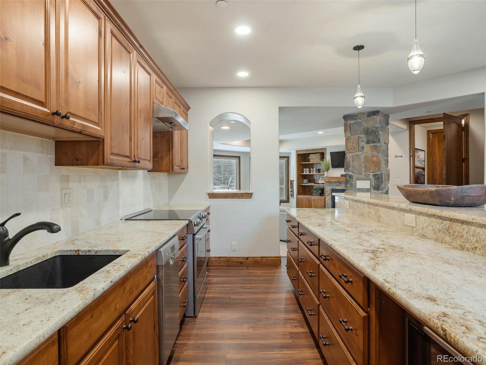 1176 Buffalo Ridge Road Castle Pines, CO 80108 - Photo 28 of 37 a kitchen with granite countertop a sink a counter space cabinets and stainless steel appliances