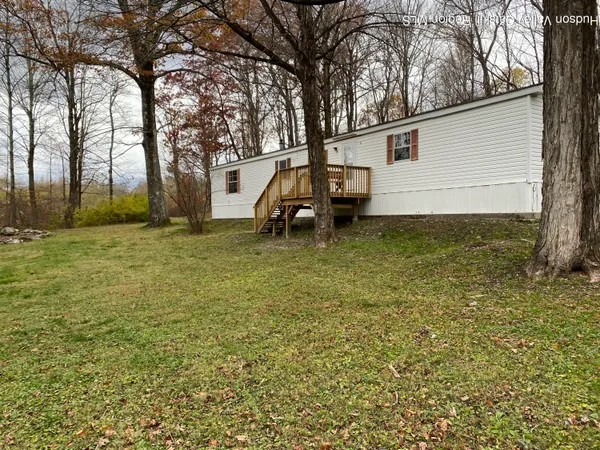 a backyard of a house with barbeque oven and large trees