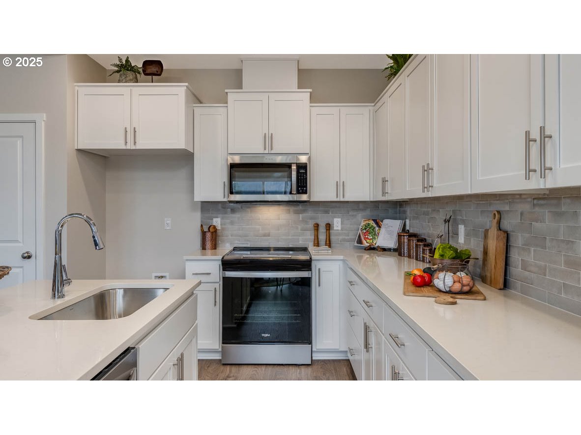 9266 Southeast Middleton Street Happy Valley, OR 97086 - Photo 5 of 14 a kitchen with stainless steel appliances granite countertop a sink dishwasher and white cabinets with wooden floor