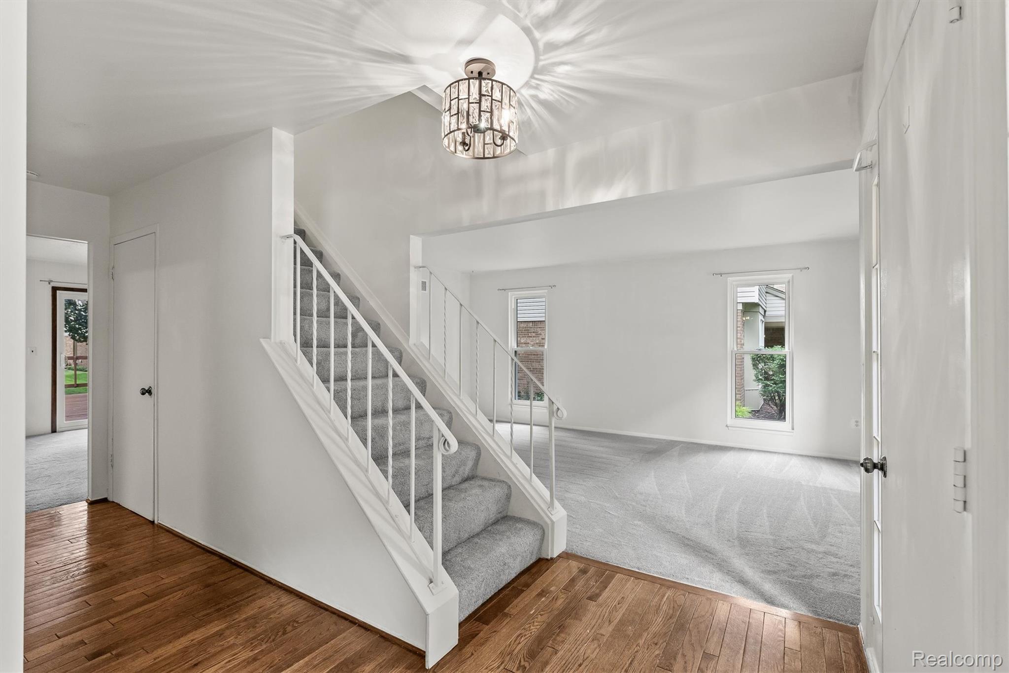 2118 Rutgers Drive Troy, MI 48085 - Photo 4 of 39 Entry foyer featuring wood-finish flooring, a modern chandelier, and a carpeted staircase with white railings