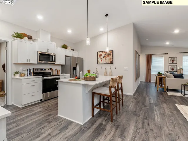 a kitchen with a sink a microwave a stove and white cabinets with wooden floor