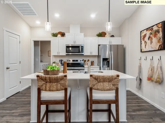 a kitchen with stainless steel appliances kitchen island granite countertop a dining table chairs and a refrigerator