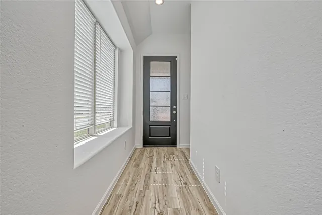 a view of a hallway with wooden floor and a bathroom
