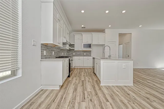 a kitchen with kitchen island wooden floors appliances and cabinets