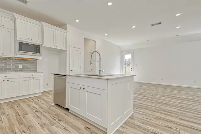 a kitchen with granite countertop white cabinets and stainless steel appliances