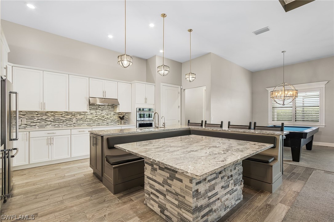 17405 Cabrini Way Estero, FL 33928 - Photo 7 of 34 a kitchen with kitchen island a wooden floor center island and stainless steel appliances