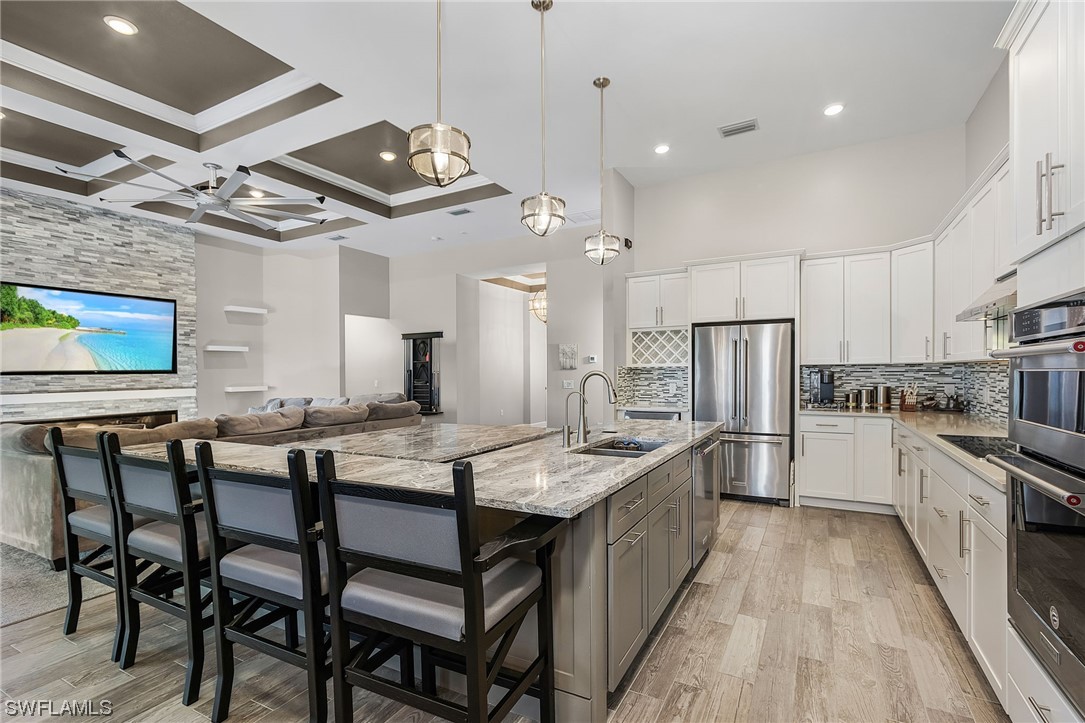 17405 Cabrini Way Estero, FL 33928 - Photo 8 of 34 a kitchen with stainless steel appliances kitchen island granite countertop a table chairs and a refrigerator