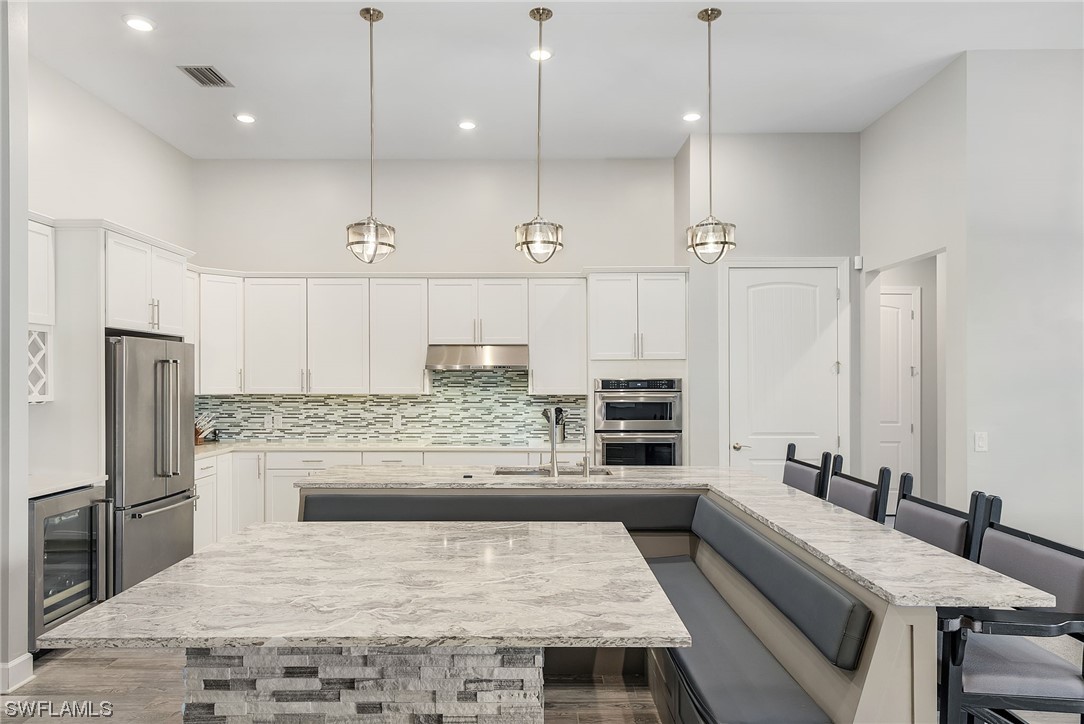 17405 Cabrini Way Estero, FL 33928 - Photo 9 of 34 a large kitchen with kitchen island a sink stainless steel appliances and a counter top space