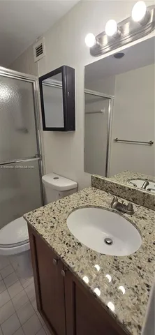 a bathroom with a granite countertop sink a toilet and a shower