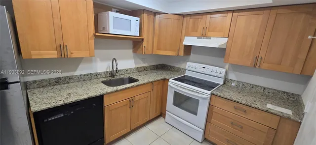 a kitchen with granite countertop cabinets stainless steel appliances and sink