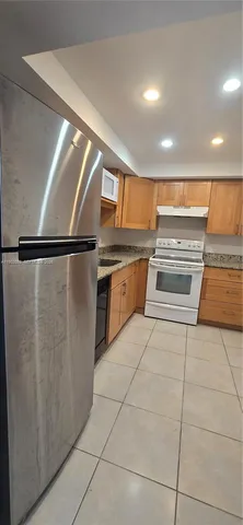 a kitchen with stainless steel appliances granite countertop a refrigerator and a stove top oven