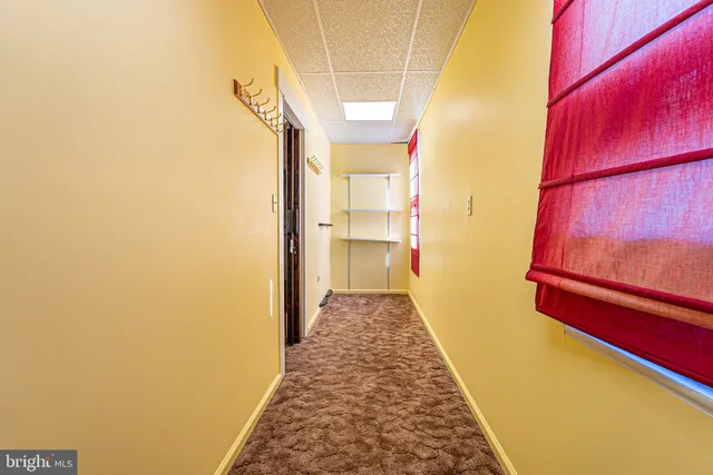 a view of a hallway with wooden floor and a bathroom