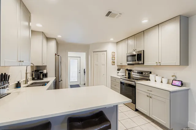 a kitchen with kitchen island sink stove and white cabinets
