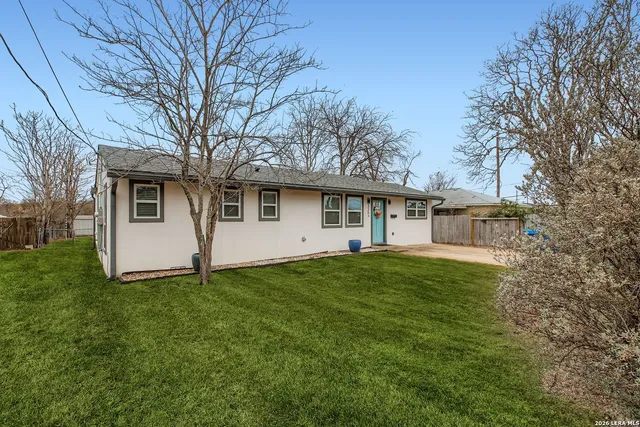 a view of a yard in front of a house with large trees