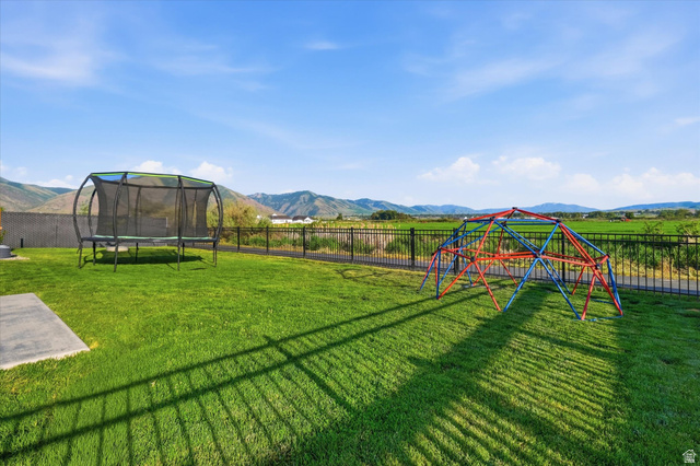 1422 West 3410th Street South Logan, UT 84321 - Photo 28 of 33 Expansive green lawn with a black metal fence bordering a scenic backdrop of mountains and fields
