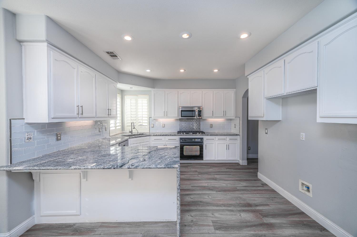 2800 Olympus Court Modesto, CA 95356 - Photo 5 of 56 a kitchen with stainless steel appliances granite countertop a sink dishwasher a refrigerator and white cabinets with wooden floor