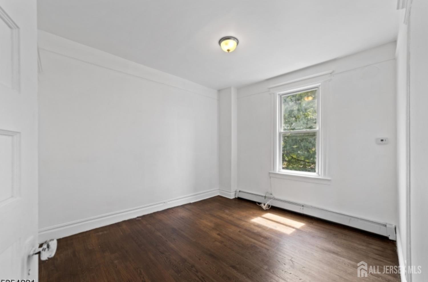 410 Chadwick Avenue, Unit 2 Newark, NJ 07112 - Photo 9 of 11 an empty room with wooden floor and windows