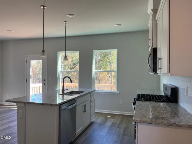 a kitchen with granite countertop a stove a sink and a wooden floor