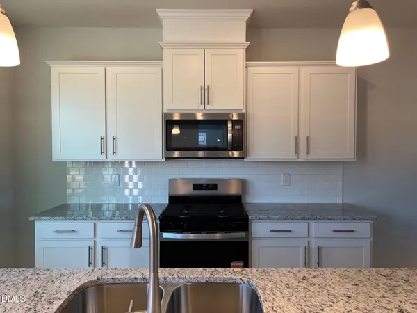 a kitchen with granite countertop white cabinets and stainless steel appliances