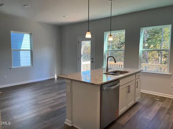 a kitchen with stainless steel appliances granite countertop cabinets a sink a window and wooden floor