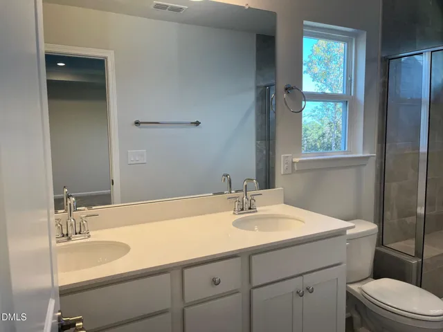 a bathroom with a sink toilet double vanity and window