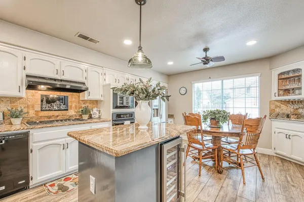 a kitchen with stainless steel appliances granite countertop a stove oven and a view of living room