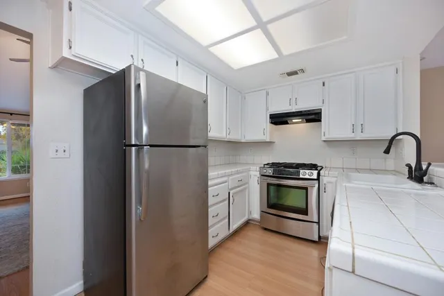 a kitchen with stainless steel appliances granite countertop a refrigerator a stove and a sink