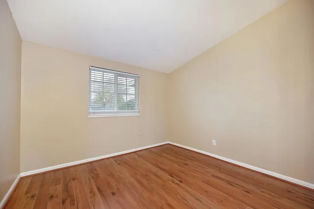 an empty room with wooden floor and mirror