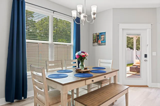 a dining room with wooden floor a chandelier a wooden table and chairs