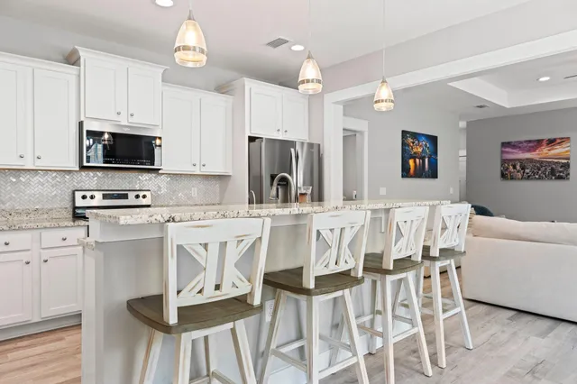 a kitchen with stainless steel appliances kitchen island granite countertop a table chairs microwave and sink